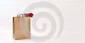 Beautiful roses in paper bag on a light background. Free space for text. Mockup for your design and logo on the package
