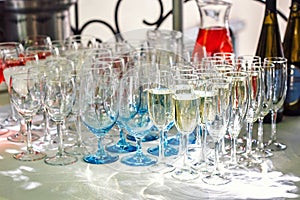 Beautiful row line of different glasses filled with champagne are lined up ready to be served on a christmas party, martini, vodka