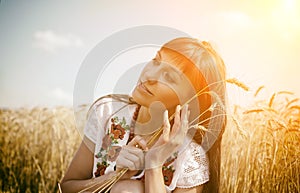 Beautiful rural girl on the wheat field on sunset