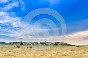 Beautiful rural landscape with a big blue sky over the hills and cropper and plowing vehicles photo