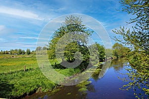 Beautiful rural lower rhine landscape with river Niers, trees, green agricultural field, blue summer sky - Germany, Viersen-SÃ¼