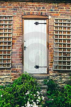 Beautiful rural white rustic door with overgrown by weeds stairs, british countryside house in the middle of nowhere