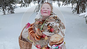 Beautiful Russian girl in a scarf on the street with a straw basket in her hands and pancakes. Pancake week