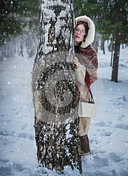 Beautiful Russian woman in a scarf in the winter playing hide an