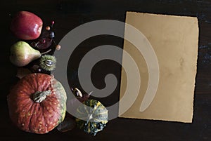 Beautiful rustic fall flat lay with leaves, pumpkins, chestnuts and old vintage paper sheet on wooden background