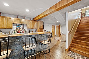 Beautiful rustic house living room interior with stools near a kitchen island and stairs