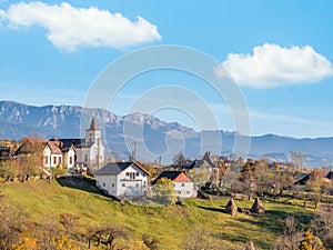 Beautiful rustic landscape in Magura village,Romania, with traditional romanian houses, a church and Piatra Craiului mountains in