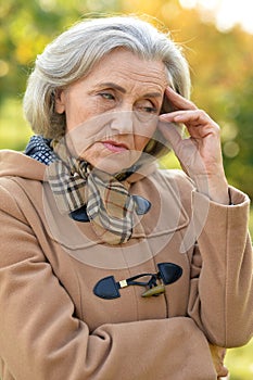 Beautiful sad elderly woman in autumn park