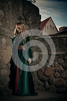 Beautiful sad girl in the medieval green dress turned away