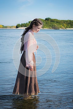 Beautiful sad girl is standing in the river