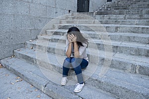 Beautiful and sad Hispanic woman desperate and depressed sitting on urban city street staircase