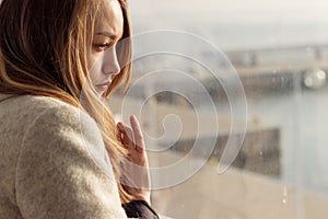 Beautiful sad lonely girl sitting near the window is missing