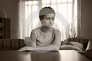 Beautiful sad young woman sitting at home