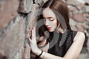 Beautiful sad young woman on a stone wall background