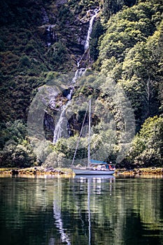 A beautiful sailboat in an anchorage in front of a waterfall