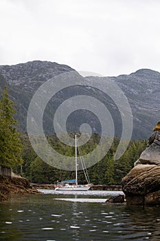 A beautiful sailboat in a remote anchorage with mountains in the background