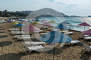 Beautiful sand beach of Kusadasi with colorful straw umbrellas and lounge chairs, Aegean Sea,Turkey.