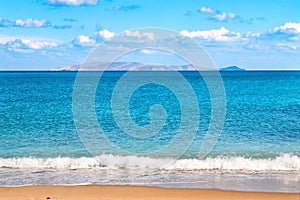 Beautiful sandy beach and soft blue sea wave on the background of the Dia island and blue sky. photo