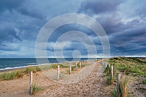 A beautiful sandy path along the ocean. Dark clouds in the sky. North Holland dune reserve, Egmond aan Zee, Netherlands