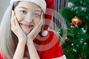 Beautiful Santa Claus woman smile happily,cheerfully and attractive,wearing hat Santa Claus,decorated christmas tree colorful