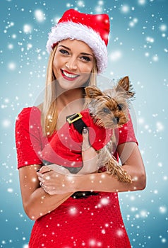 Beautiful santa woman, holding santa yorkshite terrier, snowfall background