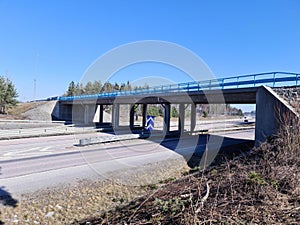 Beautiful scandinavian landscape view. Highway with speeding cars on green forest trees and blue sky background.