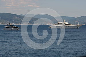 Beautiful scene of big white ships in the middle of blue water with mountains n the horizon