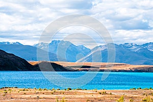 Beautiful scene of blue lake and yellow grassland with mount cook beside lake Tekapo before sunset. I