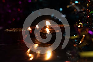 Beautiful scene with light reflection of illuminated diyas on traditional Diwali festival celebration with colorful bokeh effects photo