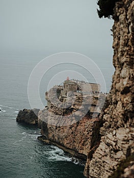 Beautiful scene of the rocky Fort of Sao Miguel Arcanjo by sea in Portugal, vertical shot photo