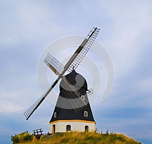 Beautiful scene of the windmill in the field with yellow grass on the blue sky background