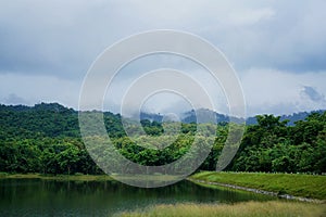 Beautiful scenery of cloud and foggy overcast greenery rain forest mountain with lake landscape at Jedkod-