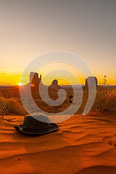 Beautiful scenery of a hat on the sand in Monument Valley, Utah with the sunset in the background