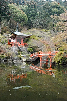 Beautiful scenery of a Japanese pagoda in a forest and a red arch bridge over a pond in the Japanese garden of Daigo-ji  Daigoji