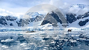 Beautiful scenery with leopard seal on ice floe and small zodiac with tourists in Paradise Bay, Antarctica photo
