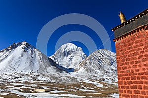 Beautiful North face of sacred Kailash mountain with old red brick building in foreground