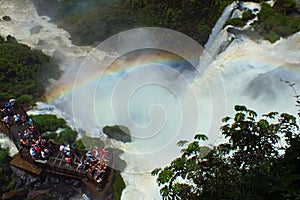 Beautiful scenery of rainbow at Iguacu Iguazu falls bridge with people close to waterfall border of Brazil and Argentina