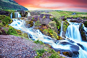 Beautiful scenery with a waterfall Kirkjufell and yellow flowers at dawn in Iceland. Exotic countries. Amazing places. Popular