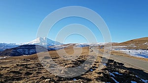 Beautiful scenic asphalt road to mount Elbrus. Panoramic view of autumn landscape. Mountains, fields, yellow grass. Travel