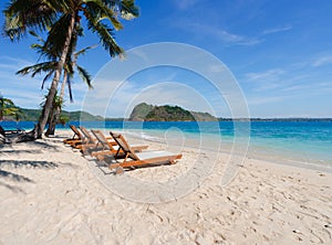 Beautiful scenic chairs on white sand beach near coconut trees with blue sea and sky on island