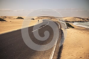 Beautiful scenic long ashalt road with desert and beach inbackgorund - concept of travel in tropical destination - holiday