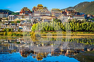 Beautiful scenic view of Ganden Sumtseling monastery with water reflection at sunset and blue sky Shangri-La Yunnan China