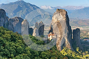 Beautiful scenic view, Orthodox Monastery of Rousanou St. Barbara, immense monolithic pillar, green and yellow foliage at the ba