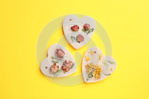 Beautiful scented sachets with flowers on yellow background
