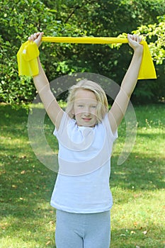 Beautiful school aged kid girl playing sports with a latex band outdoors in the park