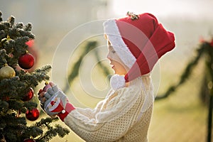 Beautiful school child, boy, decorating Christmas tree on a frosty morning