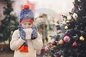 Beautiful school child, boy, holding Christmas mug, drinking tea