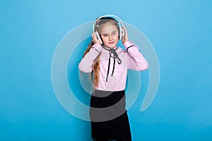 Beautiful schoolgirl girl listens to music in big headphones