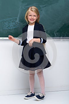 Beautiful schoolgirl standing at blackboard