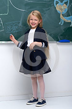 Beautiful schoolgirl standing at blackboard
